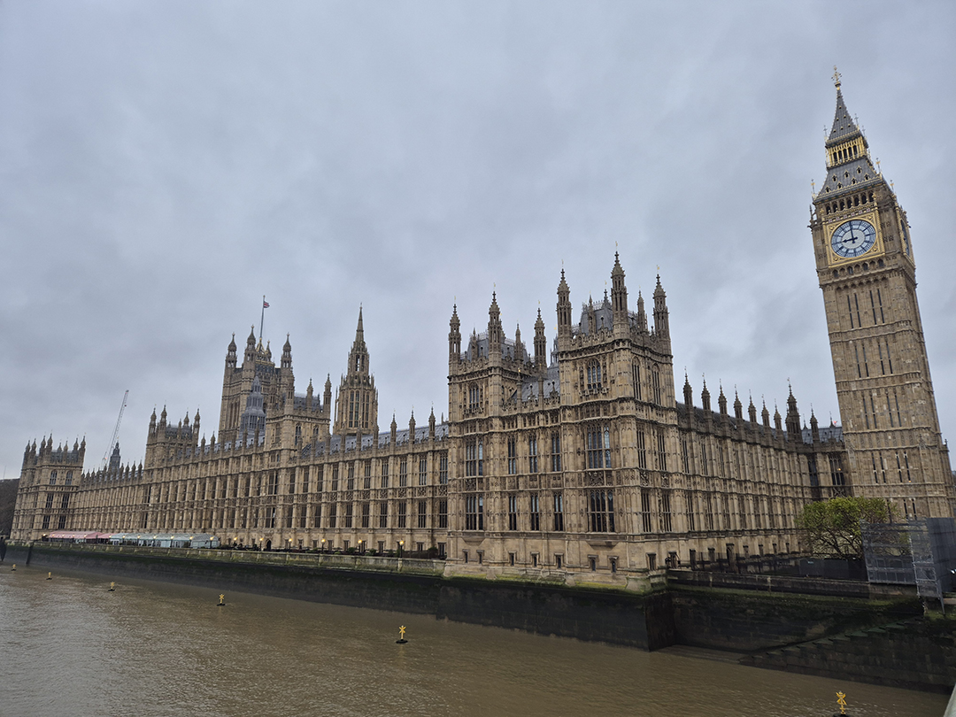 Westminstrska palača in znameniti stolp Big Ben ob reki Temzi, srce političnega dogajanja v Londonu.