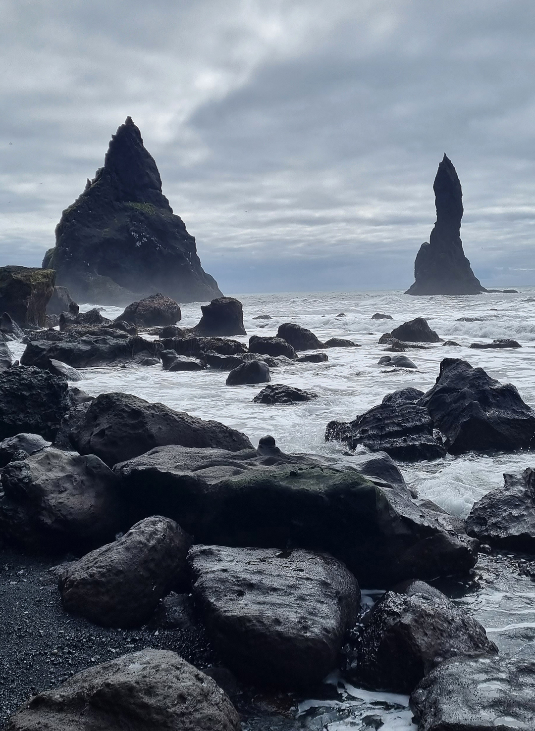 Črna peščena plaža Reynisfjara z mogočno obalo, temnim peskom in razburkanim Atlantskim oceanom na južni obali Islandije.