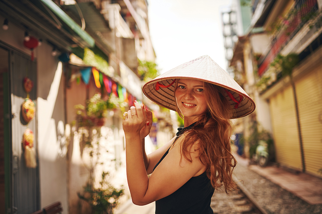 Traveller wearing a Vietnamese conical hat in Hanoi's Old Quarter.