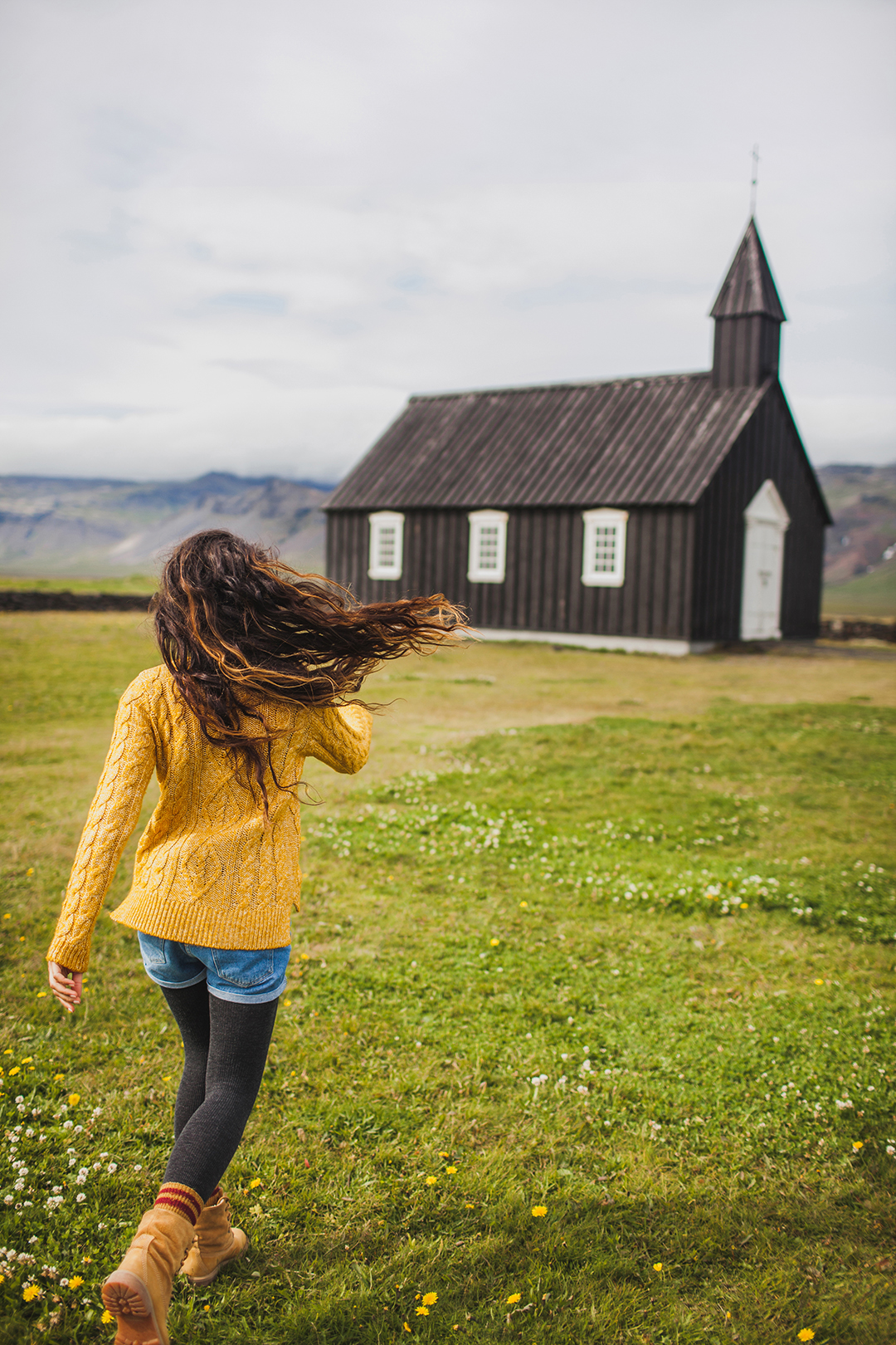 A traveller walks towards the famous black Búðakirkja Church in western Iceland, one of the country's most photographed cultural landmarks surrounded by open landscapes.
