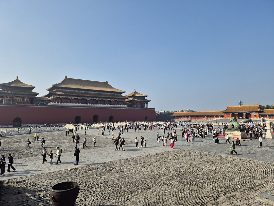 View of the magnificent Forbidden City in Beijing with visitors walking across its vast imperial courtyard.