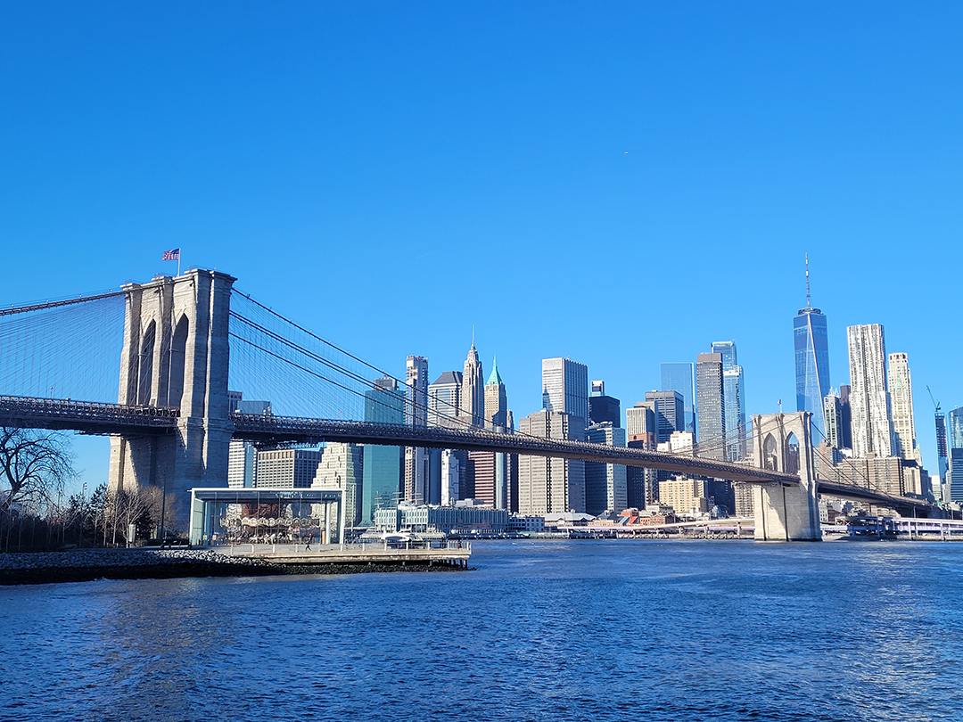 Brooklyn Bridge connects Manhattan with Brooklyn while the modern New York skyline, including One World Trade Center, rises in the background.