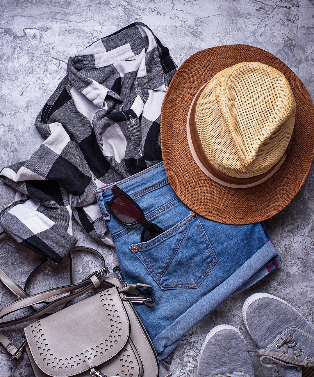 Travel clothes, a hat, sunglasses and accessories prepared for a trip, highlighting travel wardrobe choices and the importance of sustainable fashion.