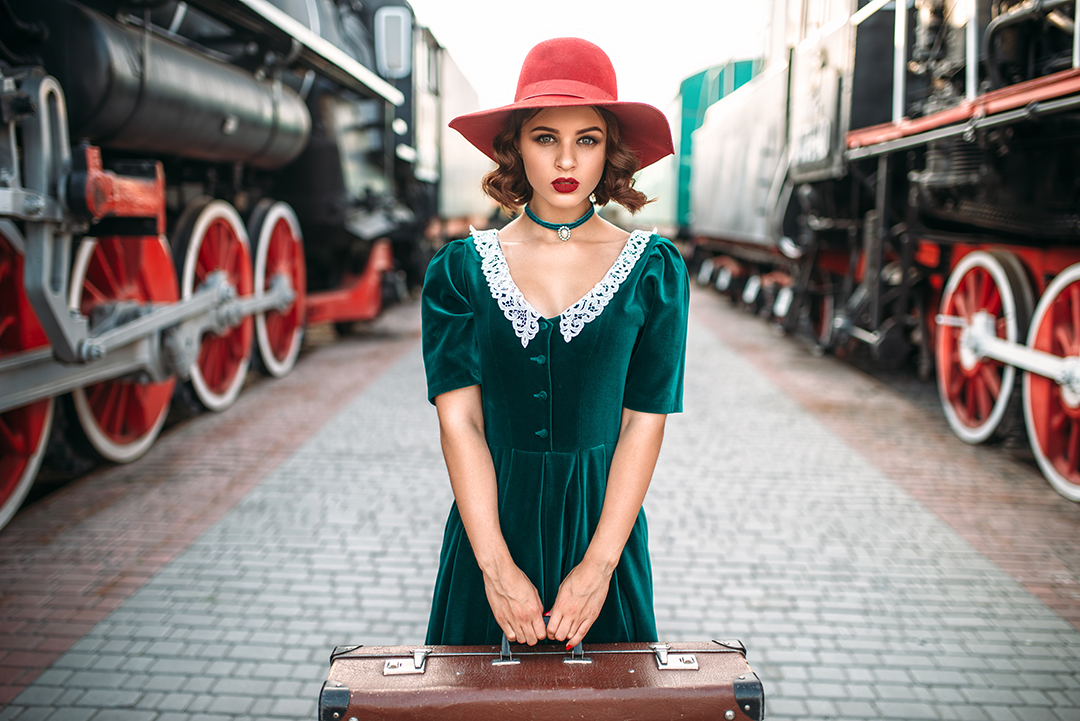 A woman wearing a vintage dress and holding an old suitcase represents sustainable fashion, clothing reuse and timeless travel style.