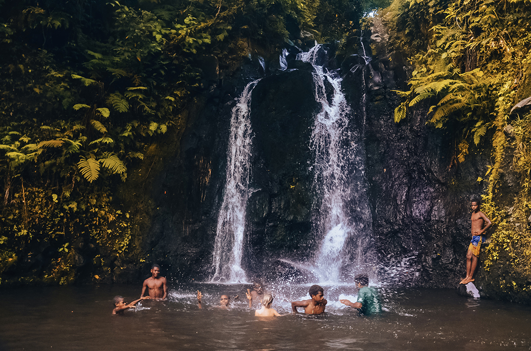 Children and travellers enjoy an evening swim beneath a waterfall in the traditional Yakel village on Tanna Island.